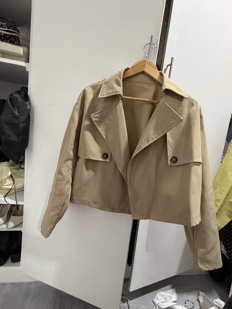 Beige Cropped Trench Jacket (Category: Coats, Jackets and Outerwear) located in Pasig City. Submitted by miss_abuelita (Listing ID 1462778062, Image 2). Description: - Cute beige cropped jacket - Mini trench coat inspired design - Two button details on the front - Ideal for layering over tops - Versatile for casual or slightly dressy outfits - Great for cooler weather.