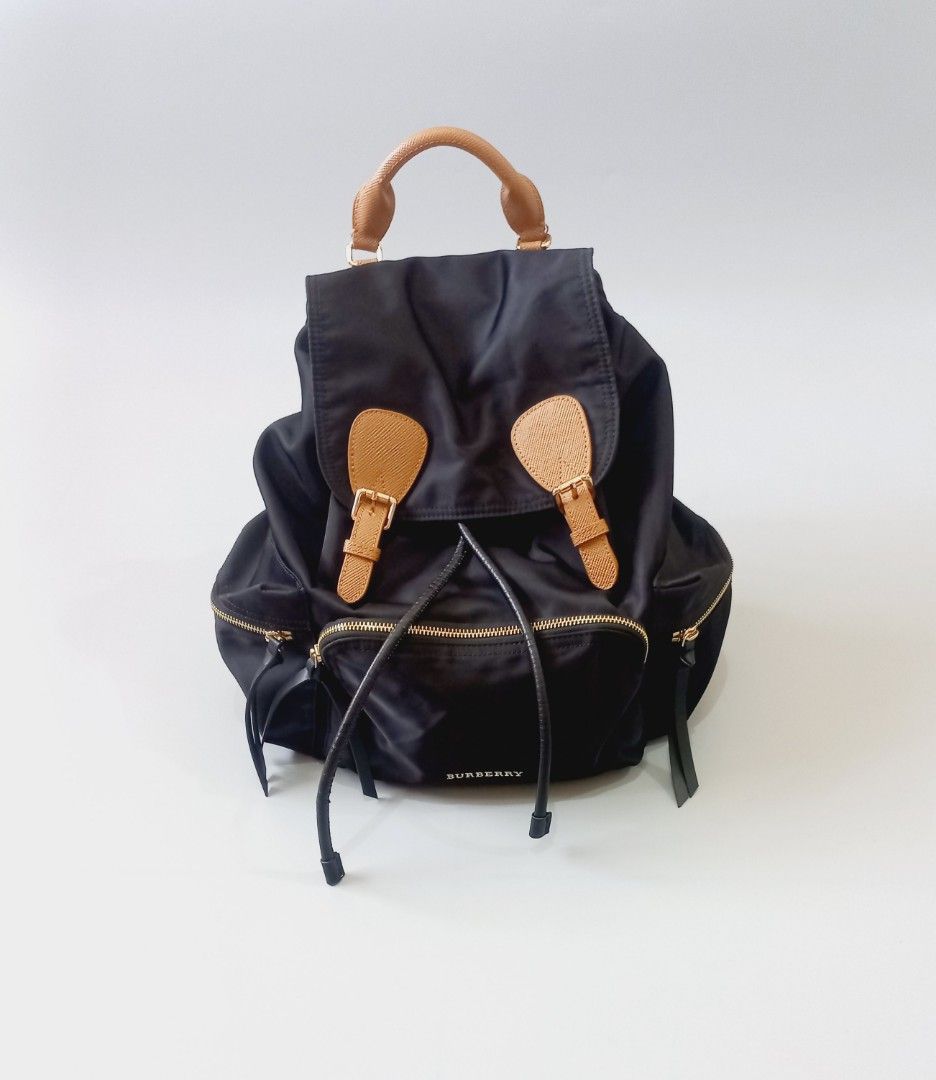 Burberry Black Nylon Leather Trim Backpack (Category: Luxury Bags & Wallets) located in Cebu City. Submitted by MrLiks_123 (Listing ID 1462851594, Image 1). Description: Authentic Burberry rucksack nylon backpack - Color: Black nylon with tan leather trim - Closure: Drawstring under flap with buckle - Hardware: Gold-tone with chain accents on straps - Features: Front zip pockets, quilted back panel - Ideal for: Everyday use casual formal event Ex
