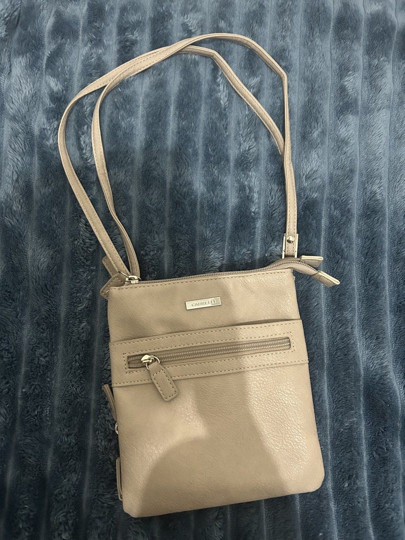 Cabrelli Beige Crossbody Bag (Category: Cross-body Bags) located in Las Pinas. Submitted by shop.ji (Listing ID 1462788958, Image 1). Description: - Lightweight Cabrelli crossbody bag - Beige color, faux leather material - Multiple zippered compartments inside for organization - Adjustable strap - Great for everyday use, travel, or errands - Easy to carry essentials.