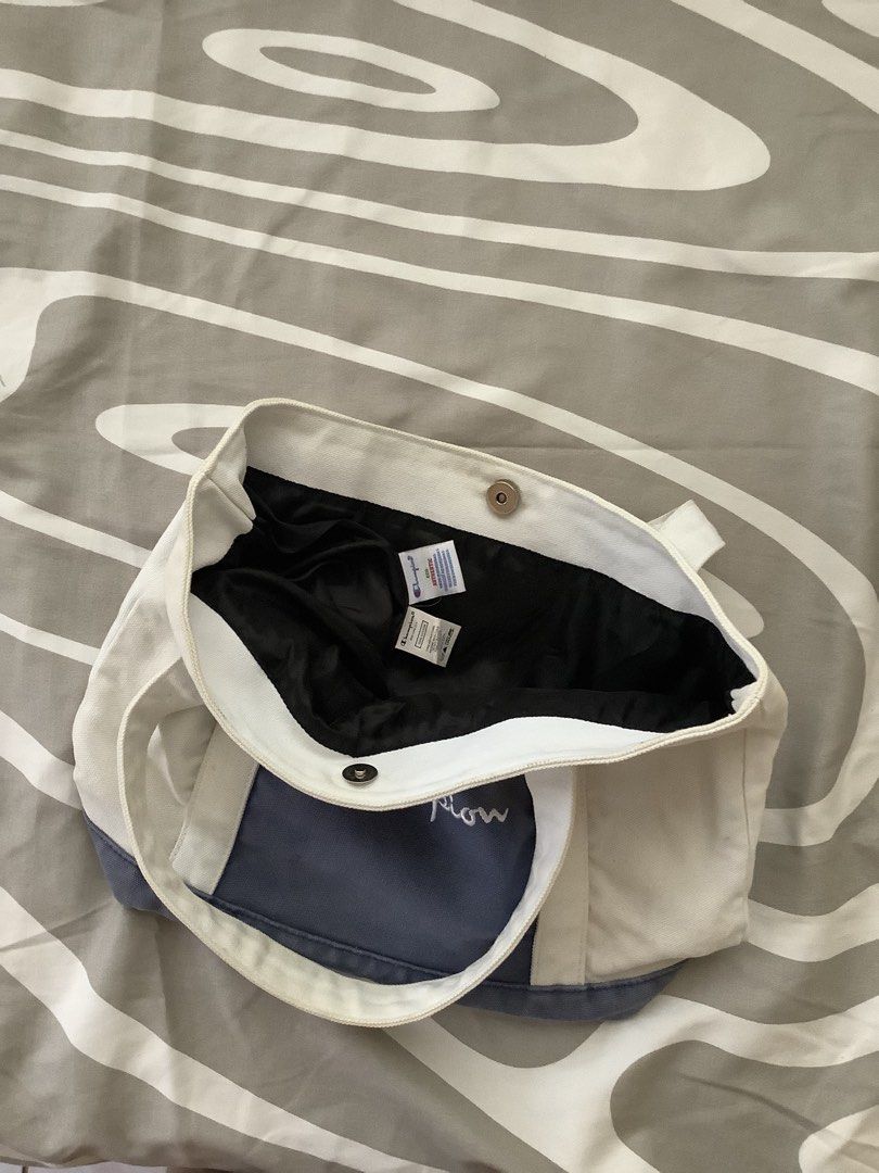 Champion Canvas Tote Bag (Category: Tote Bags) located in Cagayan de Oro. Submitted by _tstudiooo (Listing ID 1462693113, Image 3). Description: Pre-owned Medium Need wash Color: 9/10 Ecru / off-white body, paired with a light blue center panel, light blue bottom base, and white script embroidered logo - Classic Champion tote bag - Cream and navy blue colorway - Durable canvas material - Secure snap button closure - Interior lined with black fabr
