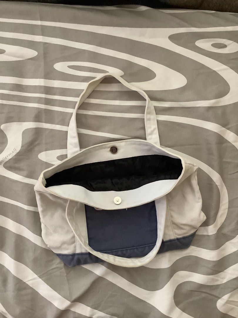 Champion Canvas Tote Bag (Category: Tote Bags) located in Cagayan de Oro. Submitted by _tstudiooo (Listing ID 1462693113, Image 2). Description: Pre-owned Medium Need wash Color: 9/10 Ecru / off-white body, paired with a light blue center panel, light blue bottom base, and white script embroidered logo - Classic Champion tote bag - Cream and navy blue colorway - Durable canvas material - Secure snap button closure - Interior lined with black fabr