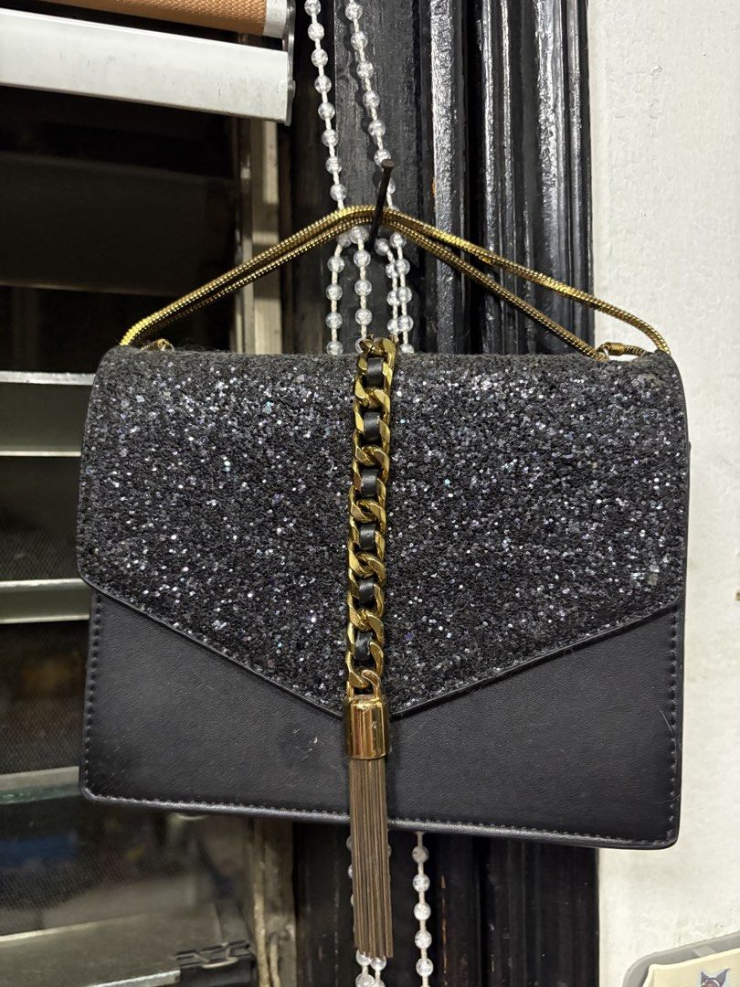 Charles & Keith Black Glitter Chain Sling Bag (Category: Cross-body Bags) located in Makati City. Submitted by cherriesforme (Listing ID 1462839144, Image 1). Description: - Stylish black sling bag - Eye-catching glitter detail on the front flap - Elegant gold chain strap - Decorative tassel accent - Convenient small mirror inside - Shows some signs of wear on the glitter (adds character!) - Ideal for nights out, parties, and special occasions.