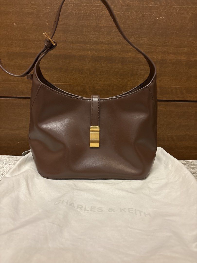 Charles & Keith Brown Shoulder Bag (Category: Shoulder Bags) located in Paranaque City. Submitted by corinne_see (Listing ID 1462838864, Image 1). Description: - Brand: Charles & Keith - Color: Brown - Style: Shoulder bag - Features: Gold buckle detail on front, interior zipped pocket, interior slip pocket - Includes: Original dust bag - Ideal for: Everyday use.