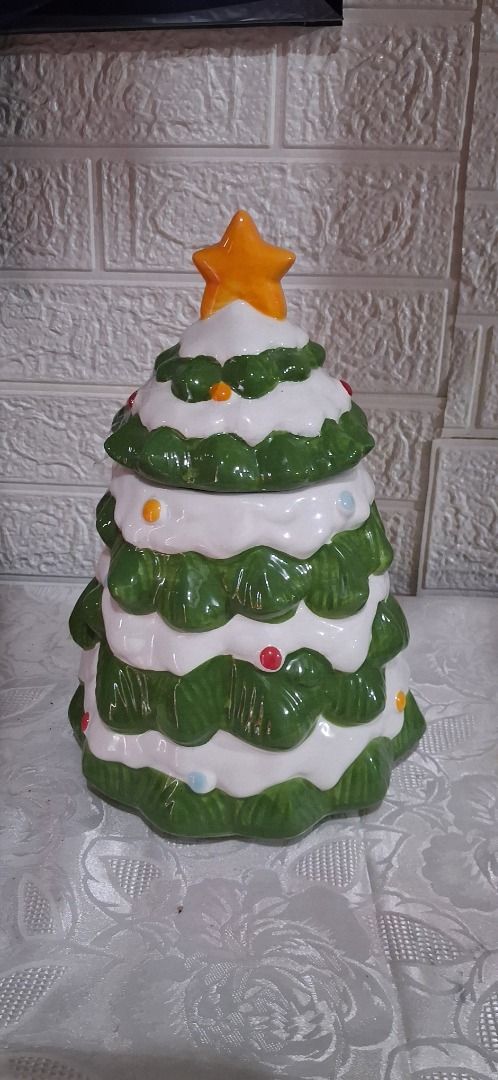 Christmas Tree Ceramic Cookie Jar with Lid (Category: Other Home Decor) located in Manila. Submitted by katkween23 (Listing ID 1462734204, Image 2). Description: - Adorable ceramic cookie jar shaped like a Christmas tree. - Features hand-painted green branches and colorful ornaments. - Includes a matching lid with a yellow star topper. - Ideal for storing cookies or as festive holiday decoration. - Adds a fun, cheerful touch to your kitchen or di