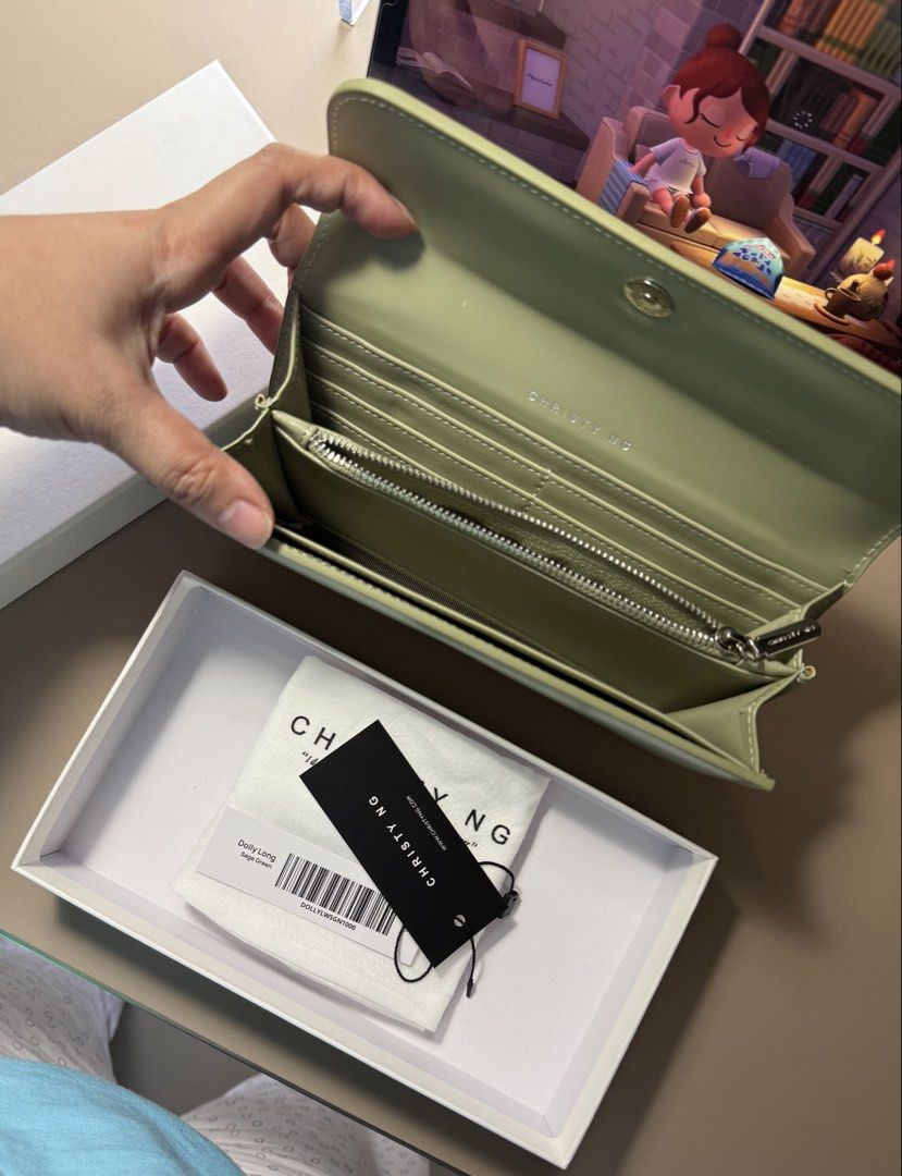 Christy Ng Long Wallet - Sage Green (Category: Wallets & Card holders) located in Manila. Submitted by tigris. (Listing ID 1462744464, Image 3). Description: - Christy Ng long wallet in elegant sage green. - Comes with original box and dust bag for safekeeping. - Ample card slots to organize your essentials. - Secure zip compartment for coins. - Chic, minimalist design with the signature Christy Ng logo. - Ideal for everyday use, blending style a