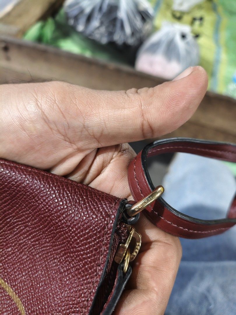 Coach Burgundy Leather Pouch with Gold Hardware (Category: Purses & Pouches) located in Maasim. Submitted by ukayganda25 (Listing ID 1462789429, Image 2). Description: - Authentic Coach pouch - Deep burgundy textured leather - Gold-tone hardware - Classic Coach creed on front - Interior Coach horse and carriage logo tag - Zipper closure - Small wrist strap attached.