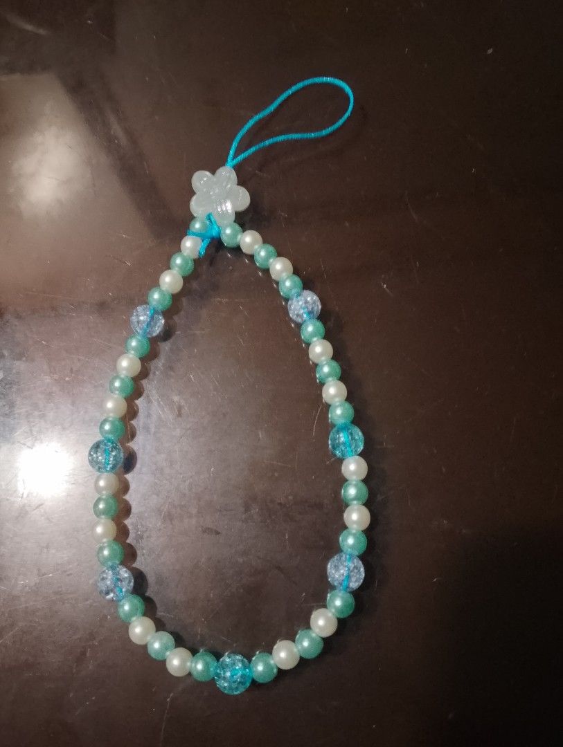 Cute Beaded Phone Strap with Flower Charm (Category: Charms) located in San Jose del Monte. Submitted by pinkpenguin.2005ya (Listing ID 1462823336, Image 1). Description: - Handmade beaded phone strap - Features pearl white and teal beads - Includes sparkly clear beads for extra flair - Adorned with a cute little flower charm - Durable blue cord loop - Adds a personal touch to your phone or bag.