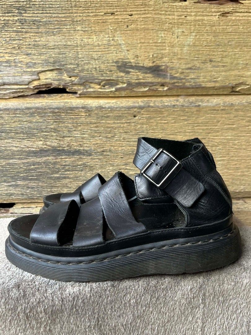 Dr. Martens Clarissa Black Leather Gladiator Platform Sandals (Category: Flats & Sandals) located in Baroy. Submitted by laudecarlfe24 (Listing ID 1462787996, Image 2). Description: - Dr. Martens black leather gladiator sandals - Platform sole for added height - Ankle strap with buckle closure - Made in Thailand - Size: 4 UK / 37 EU - Classic Dr. Martens style - Shows some signs of wear on soles and leather, consistent with use.