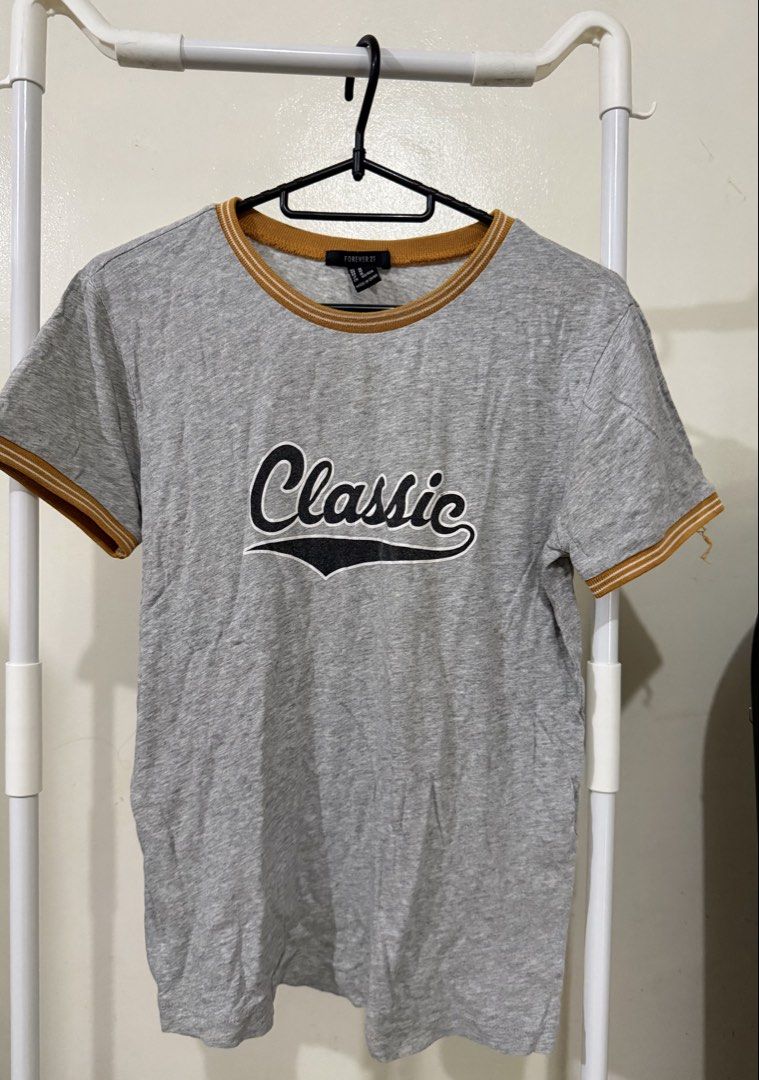 Forever 21 Grey 'Classic' Ringer T-shirt (Category: Tshirts & Polo Shirts ) located in Manila. Submitted by lovedbyan (Listing ID 1462877568, Image 1). Description: -S-M - Forever 21 -Gray t-shirt - Features 'Classic' text graphic - Contrast trim on collar and sleeves - Perfect for casual outfits.
