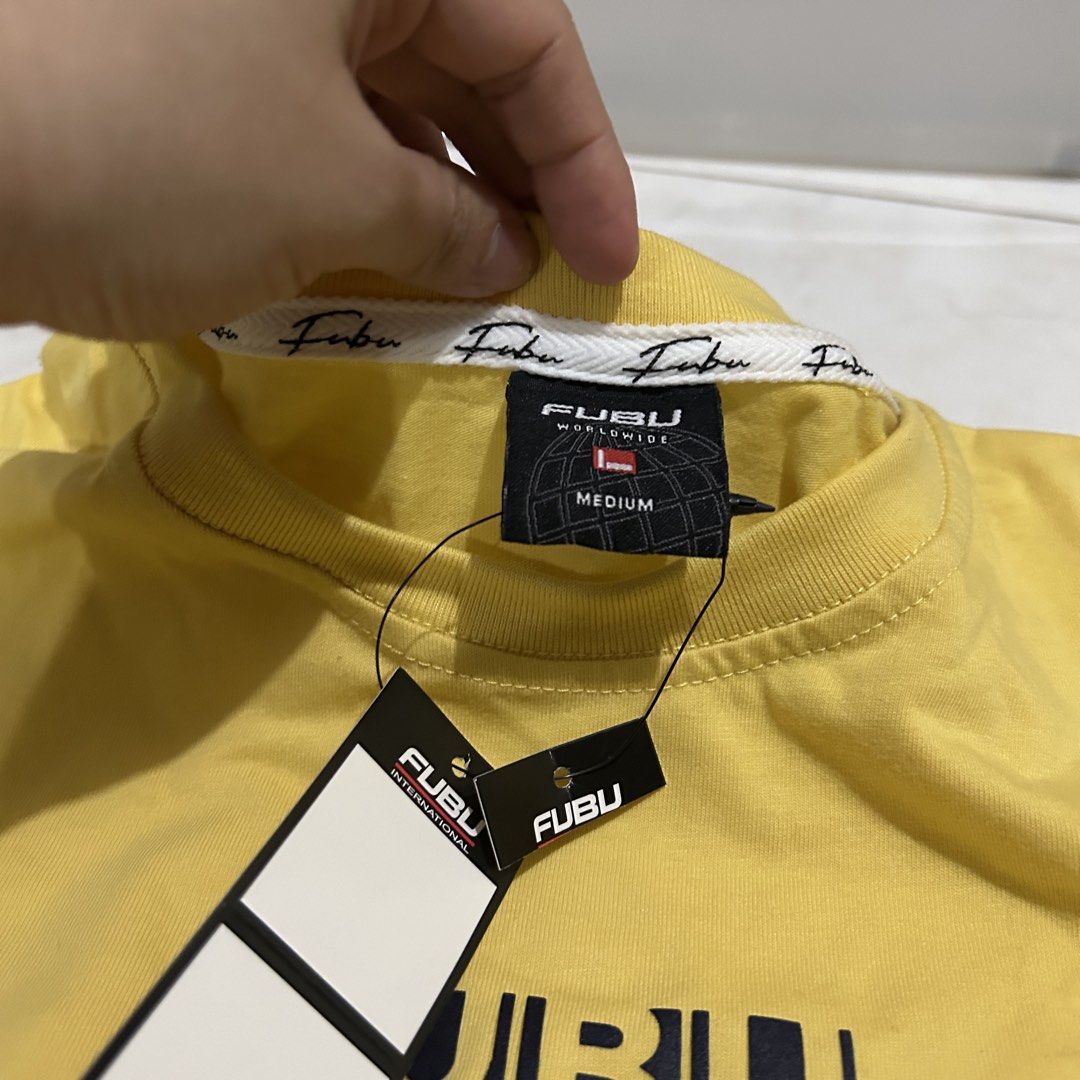 FUBU New York Yellow T-shirt (Category: Shirts) located in Bacoor. Submitted by kyespreloved (Listing ID 1462829087, Image 3). Description: - Yellow FUBU t-shirt - FUBU New York graphic on front - FUBU Worldwide tag - Size: Medium - Original tags attached - Classic streetwear style - Perfect for casual wear.