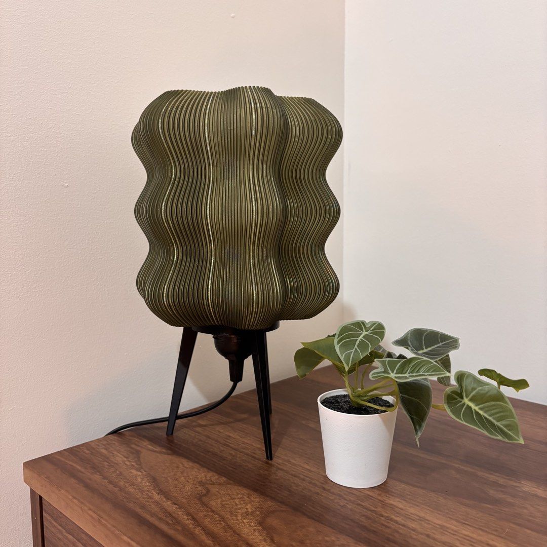 Green Wavy Lamp (with Ikea LED bulb) (Category: Lighting) located in Mandaluyong City. Submitted by taag_ (Listing ID 1462878048, Image 2). Description: - Brand new, comes in a box and paper bag - Translucent olive green - 18cm L x 18 cm W x 28 cm H - 3D printed, please allow minimal imperfections - Comes with an Ikea E27 Solhetta LED bulb (warm light) Licensed design by Eris https://makerworld.com/@eris2000.