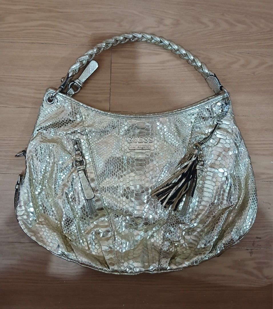 Guess Gold Snake Print Shoulder Bag (Category: Luxury Bags & Wallets) located in Daraga. Submitted by thethriftcity2024 (Listing ID 1462690385, Image 1). Description: - Stylish gold Guess Hobo shoulder bag - Eye-catching snake print texture - Comfortable braided strap - Decorative tassel detail - Front and back zip pockets for secure storage - Interior lined with Guess logo - Durable PVC and polyester material PRISTINE CONDITION 9.8/10 COLOR RATE