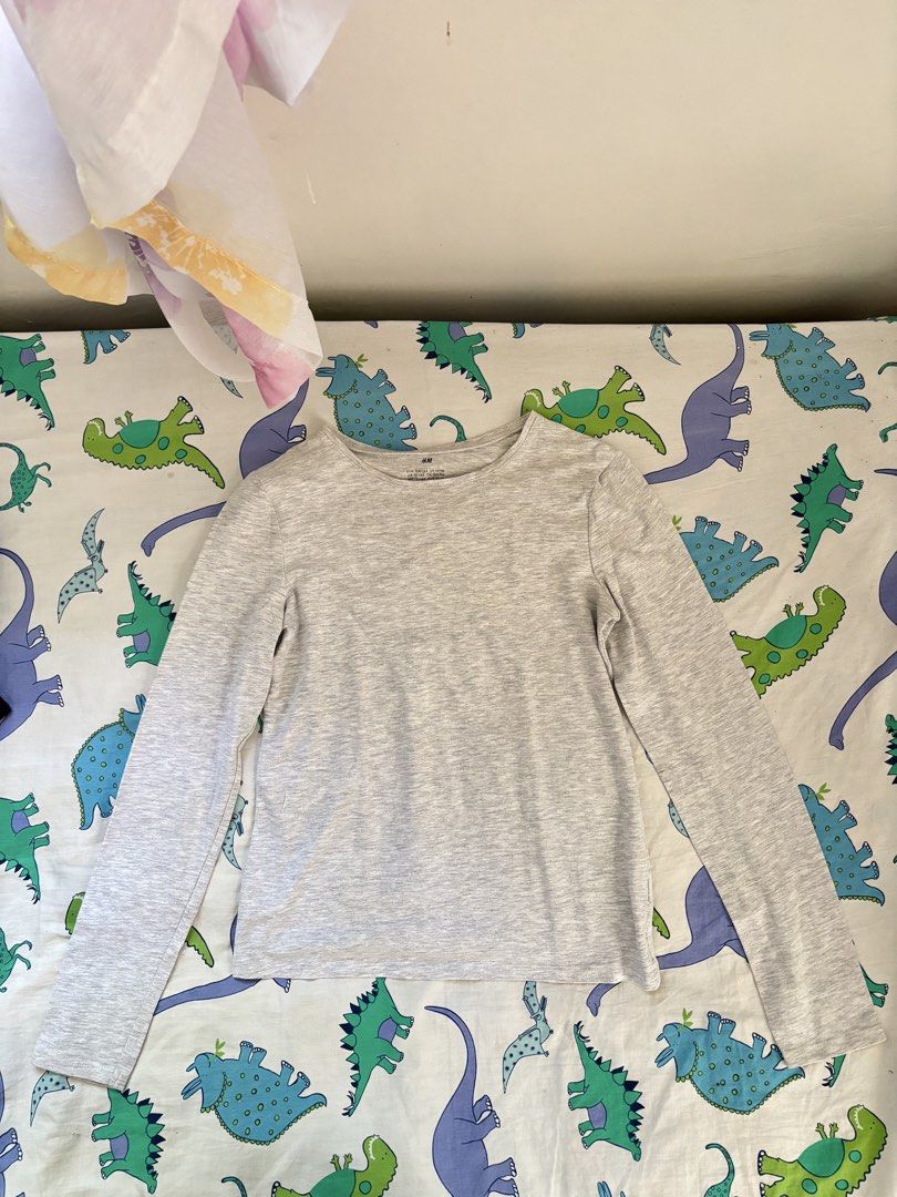 H&M Grey Long Sleeve Shirt (Category: Community) located in Paranaque City. Submitted by ggg.bin (Listing ID 1462782375, Image 1). Description: - Size S - Grey long-sleeve top from H&M - Soft and comfortable fabric - Features a fun dinosaur print on the background - Ideal for everyday wear, layering, or wearing solo - Easily pairs with jeans or shorts.