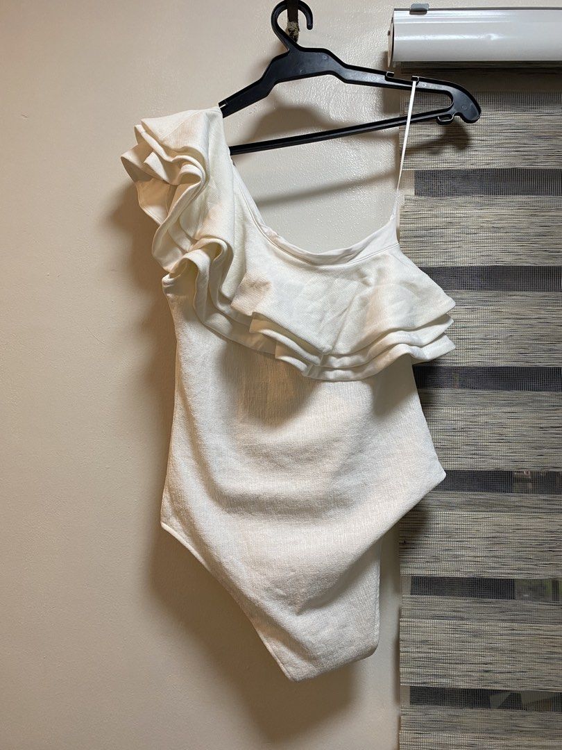 H&M White One-Shoulder Ruffle Bodysuit Size S (Category: Others Tops) located in Cavite. Submitted by yc.shoppemnl (Listing ID 1462788947, Image 1). Description: White one-shoulder bodysuit from H&M. Features a ruffled detail on the shoulder. Made with a polyester and elastane blend. Perfect for layering or wearing on its own. Comfortable and stylish. Size S. Pretty in actual.