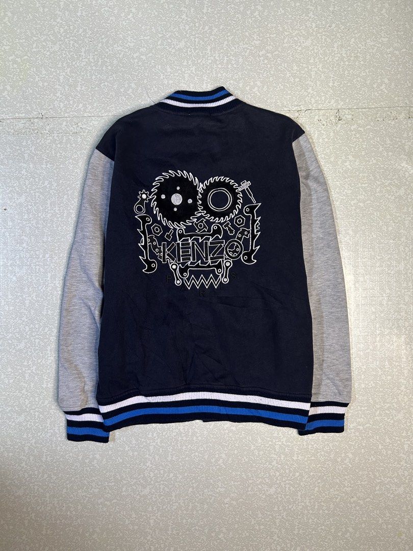 Kenzo Paris Varsity Jacket (Category: Coats, Jackets and Outerwear) located in Dasmarinas. Submitted by insaurigaj60770 (Listing ID 1462716484, Image 2). Description: - Authentic Kenzo Paris varsity jacket - Color: Navy blue body with grey sleeves - Iconic Kenzo logo and graphics on the back - Classic ribbed collar, cuffs, and hem with blue and white stripes - Easy snap button closure - Size: Large (L).