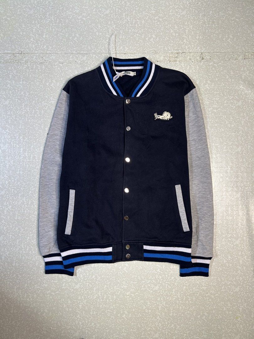 Kenzo Paris Varsity Jacket (Category: Coats, Jackets and Outerwear) located in Dasmarinas. Submitted by insaurigaj60770 (Listing ID 1462716484, Image 1). Description: - Authentic Kenzo Paris varsity jacket - Color: Navy blue body with grey sleeves - Iconic Kenzo logo and graphics on the back - Classic ribbed collar, cuffs, and hem with blue and white stripes - Easy snap button closure - Size: Large (L).