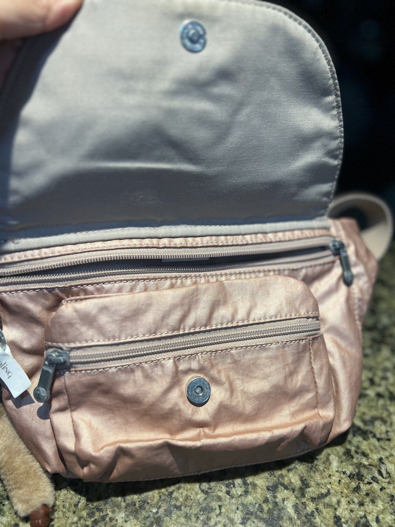 Kipling Rose Gold Nylon Waist Bag with Monkey Charm (Category: Purses & Pouches) located in Manila. Submitted by kathlv (Listing ID 1462827551, Image 2). Description: - Cute Kipling waist bag in shimmery rose gold. - Made from durable nylon. - Features a main zippered compartment and a front zippered pocket. - Comes with the iconic Kipling monkey charm. - Adjustable strap for a comfortable fit. - Ideal for travel or everyday use..
