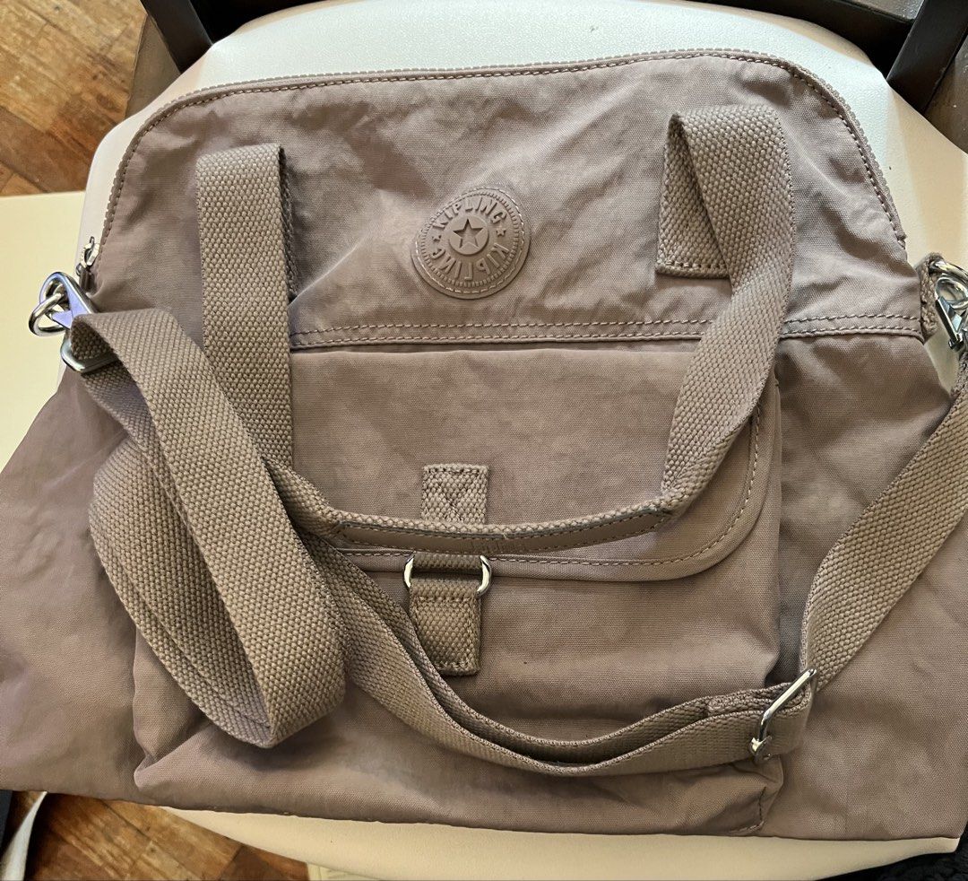 Kipling Tote Bag Taupe Nylon Shoulder Bag (Category: Tote Bags) located in Mandaluyong City. Submitted by yamcsf47597 (Listing ID 1462746387, Image 1). Description: - Taupe Kipling tote bag - Durable nylon material - Front pocket with snap closure - Adjustable shoulder strap - Silver-toned zippers and hardware - Iconic Kipling logo on the front - Ideal for everyday use.