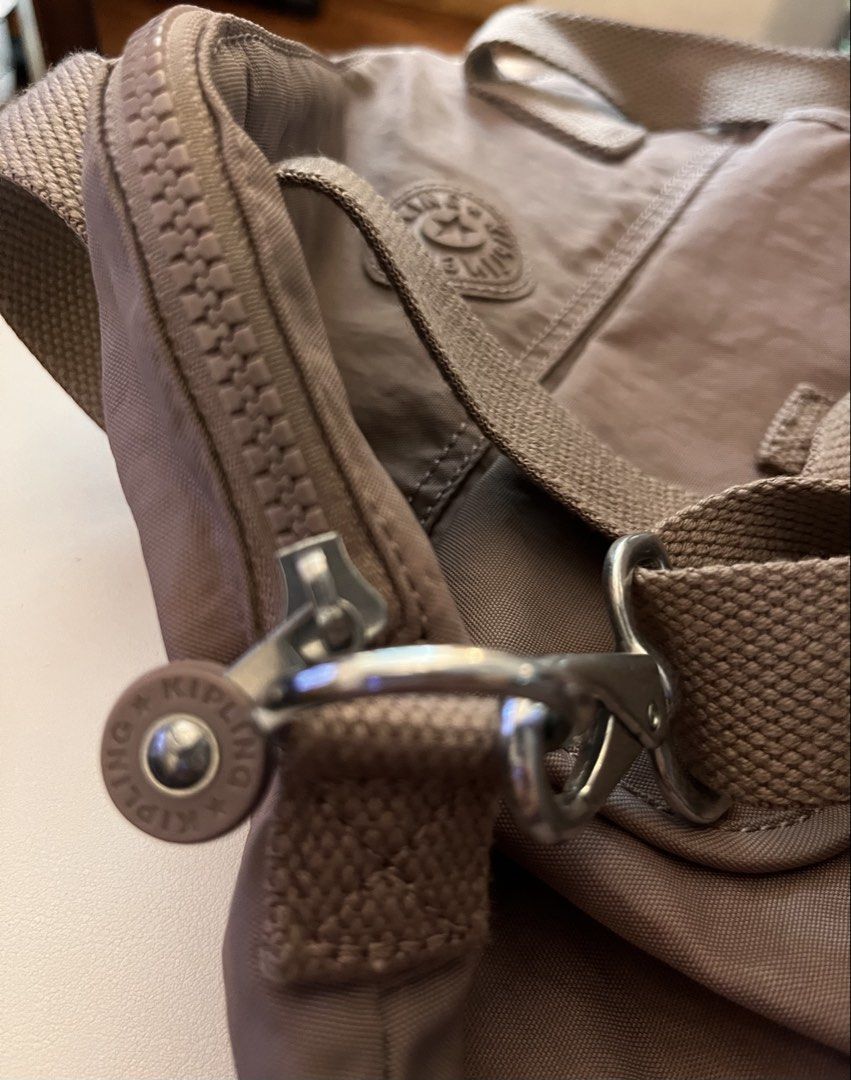 Kipling Tote Bag Taupe Nylon Shoulder Bag (Category: Tote Bags) located in Mandaluyong City. Submitted by yamcsf47597 (Listing ID 1462746387, Image 3). Description: - Taupe Kipling tote bag - Durable nylon material - Front pocket with snap closure - Adjustable shoulder strap - Silver-toned zippers and hardware - Iconic Kipling logo on the front - Ideal for everyday use.