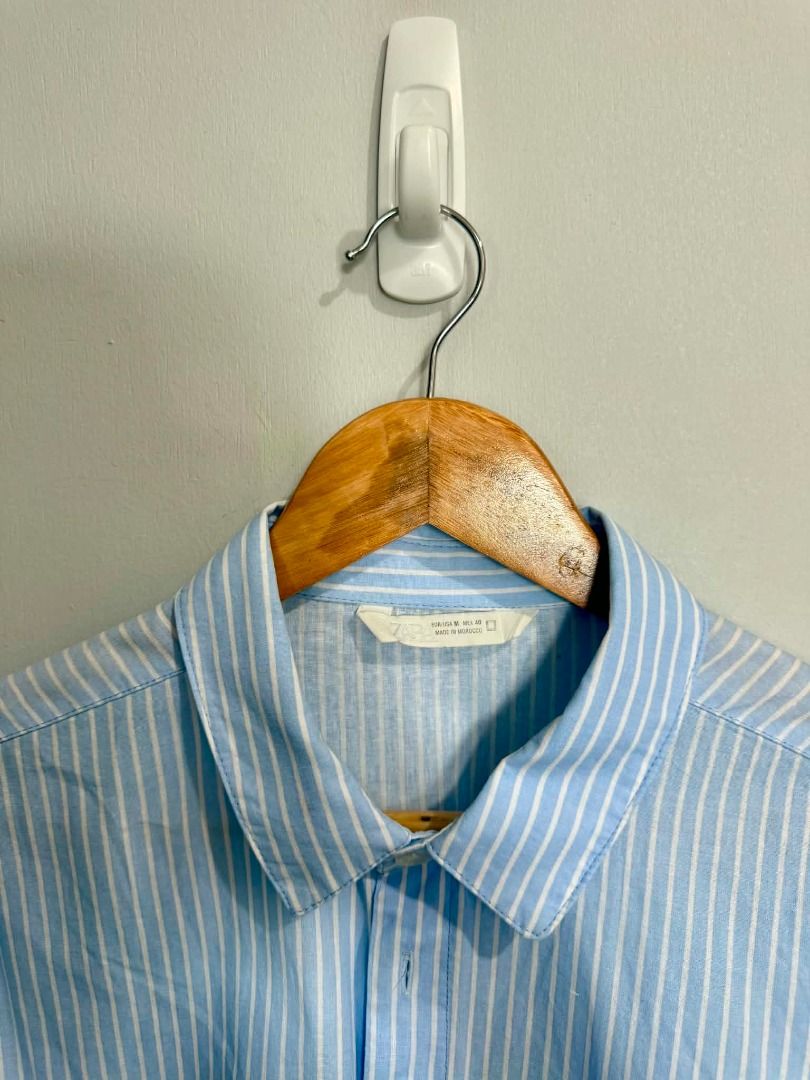 Light Blue Striped Button-Up Shirt with White Script Print (Category: Activewear) located in Caloocan City. Submitted by capurcosjo05601 (Listing ID 1462705295, Image 2). Description: - Light blue shirt with white vertical stripes - White script print on the front - Button-up style with a collar - Long sleeves - Estimated size: Medium - Perfect for casual outfits.