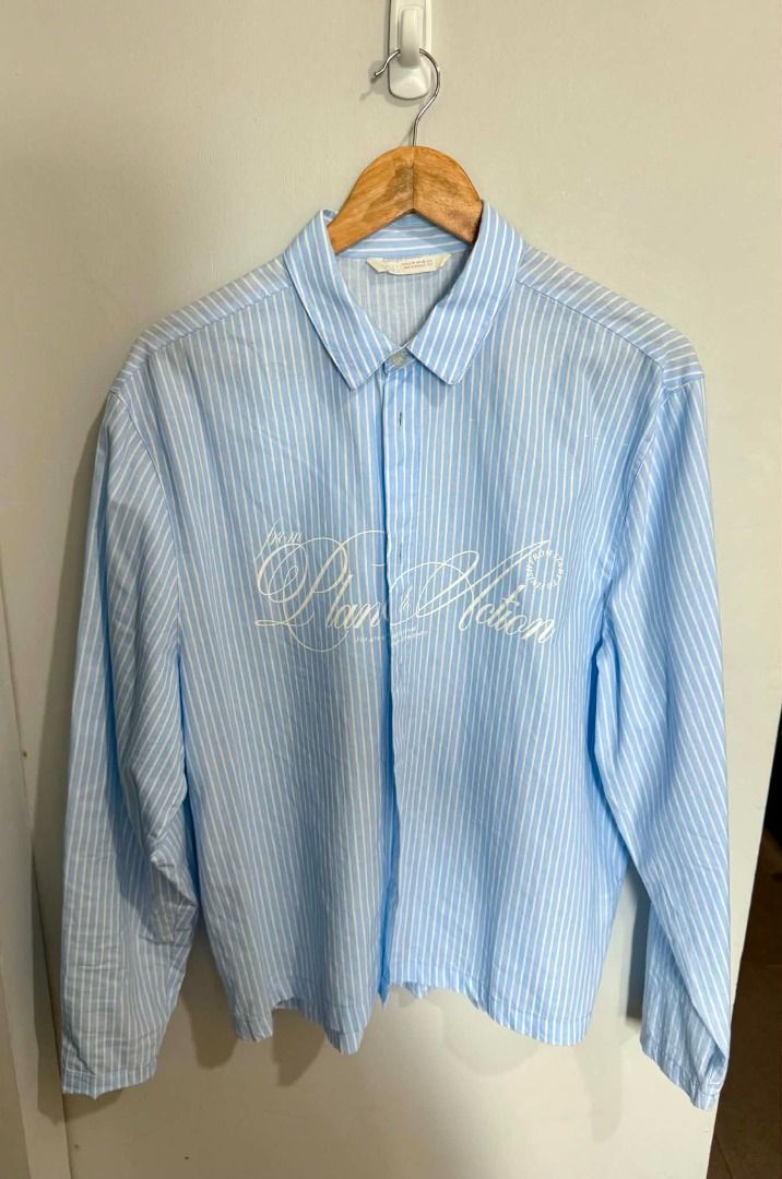 Light Blue Striped Button-Up Shirt with White Script Print (Category: Activewear) located in Caloocan City. Submitted by capurcosjo05601 (Listing ID 1462705295, Image 1). Description: - Light blue shirt with white vertical stripes - White script print on the front - Button-up style with a collar - Long sleeves - Estimated size: Medium - Perfect for casual outfits.