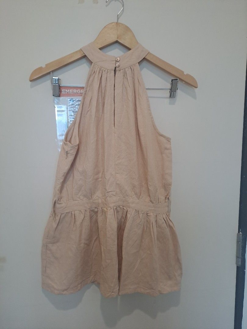 Linen blend halter beige (Category: Sleeveless) located in Manila. Submitted by joanbalde39643 (Listing ID 1462785084, Image 2). Description: This garment is a chic beige halter-neck peplum top featuring a gathered neckline, an elasticated dropped waist, and a flared, ruffled hem. Crafted from a lightweight woven fabric like cotton or linen, its minimalist, breezy silhouette makes it highly versatile for warm weather..