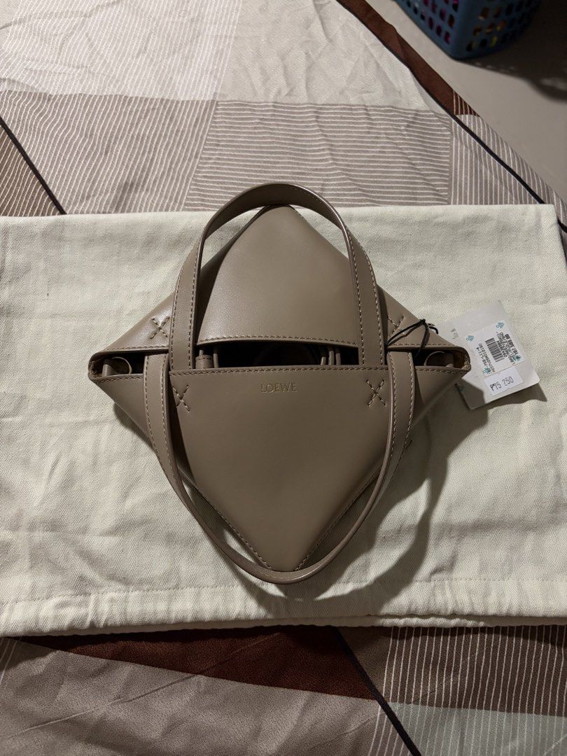 LOEWE Puzzle Fold Mini Bag Sand Color (Category: Tote Bags) located in Cavite. Submitted by tripleKgels (Listing ID 1462870195, Image 2). Description: - Loewe Puzzli Fold Tote Bag - Color: Taupe/Sand - Material: Leather - Features: Detachable shoulder strap, unique folded design - Versatile: Ideal for daily use or special occasions.