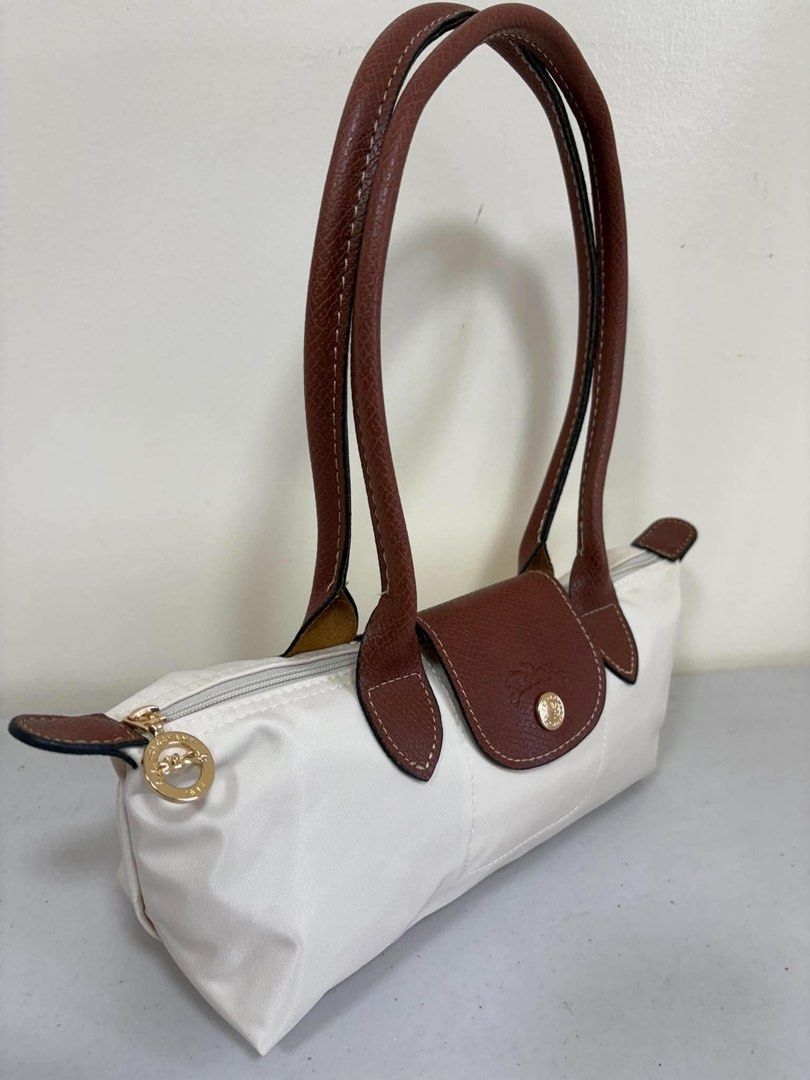 Longchamp Le Pliage Pouch White Leather Trim (Category: Luxury Bags & Wallets) located in Los Banos. Submitted by ukaynidizkie (Listing ID 1462872309, Image 2). Description: - White Longchamp pouch - Brown leather handles and trim - Zipper closure - Interior small pocket - Ideal for everyday essentials - Clean inside and out - Ready for a new owner.