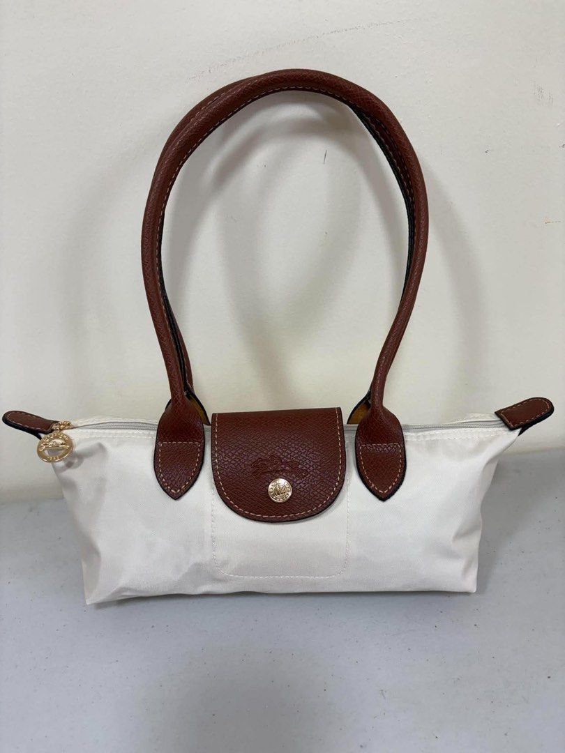 Longchamp Le Pliage Pouch White Leather Trim (Category: Luxury Bags & Wallets) located in Los Banos. Submitted by ukaynidizkie (Listing ID 1462872309, Image 1). Description: - White Longchamp pouch - Brown leather handles and trim - Zipper closure - Interior small pocket - Ideal for everyday essentials - Clean inside and out - Ready for a new owner.