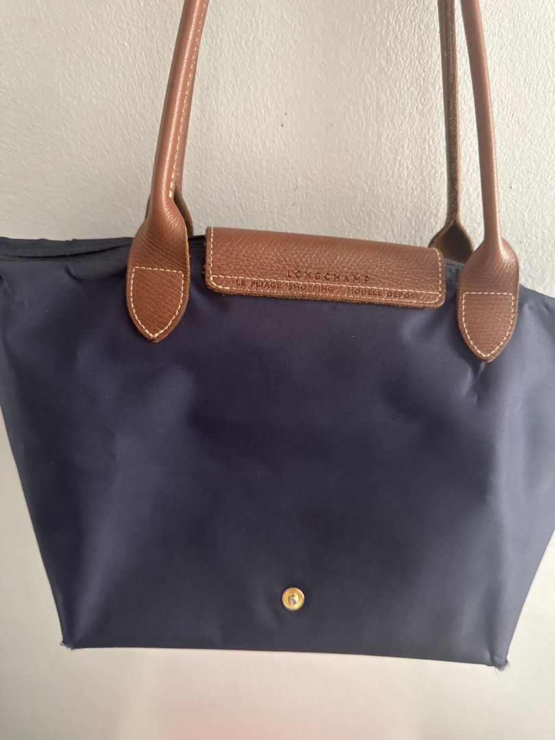 Longchamp Le Pliage Tote Bag Navy Blue (Category: Luxury Bags & Wallets) located in Manila. Submitted by decluterthings888 (Listing ID 1462706548, Image 2). Description: - Classic Longchamp Le Pliage tote bag - Color: Navy blue nylon with brown leather handles and trim - Closure: Snap closure - Interior: One interior pocket - Perfect for: Everyday use, travel, carry-on.