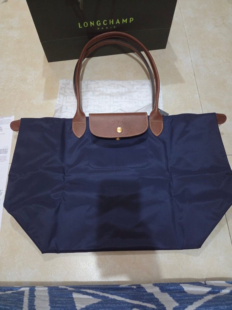 Longchamp Le Pliage Tote Bag Navy Blue (Category: Luxury Bags & Wallets) located in Manila. Submitted by rabbitprimavera (Listing ID 1462863747, Image 2). Description: - Authentic Longchamp Le Pliage tote bag in Large - Classic navy blue nylon with brown leather handles and trim - Includes original shopping bag and tag - Bought in Istanbul 1 week ago - Can provide proof of purchase (receipt) rfs: extra.