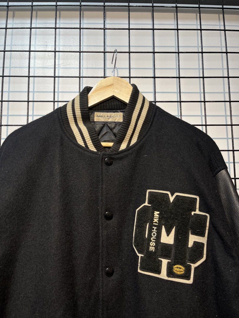 Miki House Varsity Jacket Black Leather Sleeves (Category: Coats, Jackets and Outerwear) located in Taal. Submitted by thrift_deals23 (Listing ID 1462786371, Image 2). Description: - Classic Miki House varsity jacket - Black wool body with leather sleeves - Embroidered logo on front - 'MIKI HOUSE' embroidery on back - Ribbed collar, cuffs, and hem - Button-up closure - Great addition to any collection.