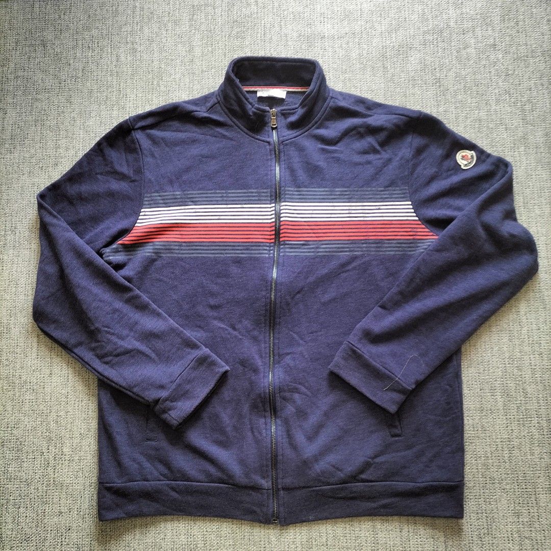 Moncler Navy Blue Track Jacket Size 3XL (Category: Coats, Jackets and Outerwear) located in Taytay. Submitted by calmtree-6248 (Listing ID 1462808009, Image 1). Description: - Navy blue Moncler track jacket - Size: 3XL - Horizontal chest stripes in red, white, and grey - Moncler logo patch on left sleeve - Full zip closure - Ideal for casual wear.