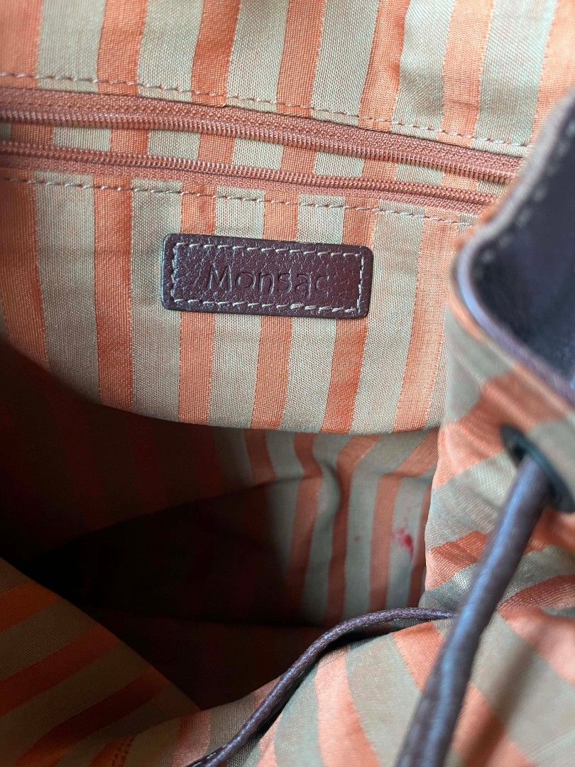 Monsac Leather Backpack - Burgundy (Category: Backpacks) located in Baroy. Submitted by laudecarlfe24 (Listing ID 1462790970, Image 3). Description: - Burgundy leather backpack from Monsac - Flap closure with drawstring underneath - Two side pockets - Zippered pocket on the back - Interior with striped lining - Adjustable straps - Shows some signs of wear on the leather, consistent with a used item.