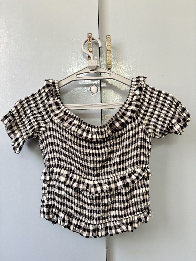 Moon River Off-Shoulder Top Size L (Category: Blouses) located in Paranaque City. Submitted by ggg.bin (Listing ID 1462773229, Image 1). Description: - Brand: Moon River - Style: Off-shoulder top - Pattern: Black and white gingham - Features: Smocked bodice, ruffled hem, short sleeves with ruffled cuffs - Versatile: Pairs well with jeans or shorts - Occasion: Casual outings, everyday wear.