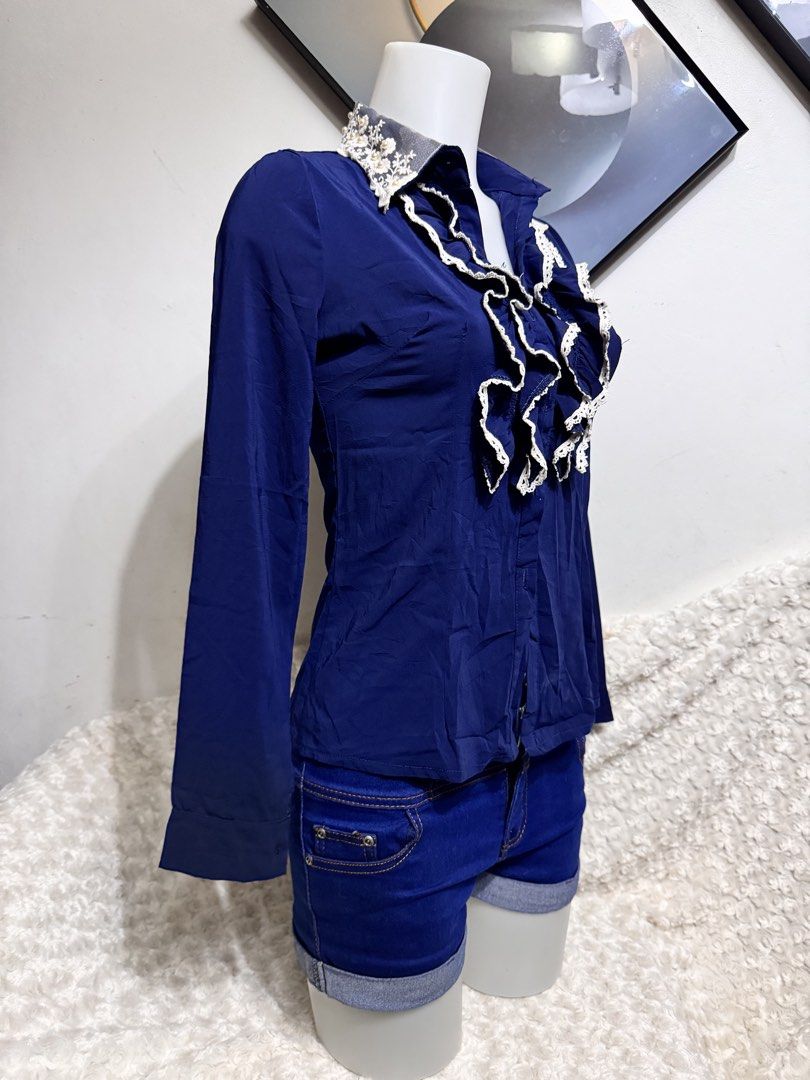 Navy Blue Ruffled Button-Up Blouse with Lace Collar (Category: Blouses) located in Marikina City. Submitted by lorradel (Listing ID 1462750398, Image 2). Description: - missing buttons bahala ka na maglagay - free with purchase - Navy blue long-sleeved blouse - Features a ruffled front with white lace trim - Lace detailing on the collar - Button-up front - Versatile for pairing with jeans or shorts - Ideal for a smart casual look - MAY HAVE some 