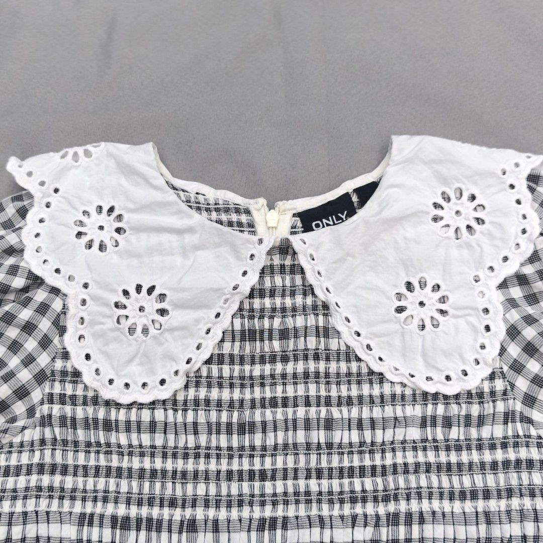 ONLY Black & White Gingham Smocked Top with Eyelet Collar (Category: Blouses) located in Alfonso Lista (Potia). Submitted by ak_collection.03 (Listing ID 1462802452, Image 2). Description: Elevate your wardrobe with this stylish Cottagecore / Coquette aesthetic peplum blouse from ONLY. Features a classic monochrome gingham plaid pattern, an elasticized smocked bodice for a flattering stretchy fit, and a dramatic statement white eyelet lace collar