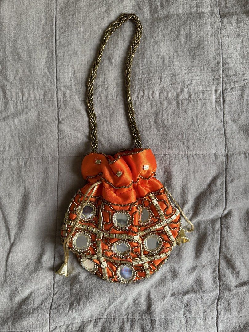 Orange Beaded Mirror Potli Bag with Gold Handle (Category: Purses & Pouches) located in Davao. Submitted by lyscapuno (Listing ID 1462685653, Image 2). Description: - Vibrant orange potli bag - Intricate beadwork and mirror embellishments - Braided gold handle - Secure drawstring closure - Ideal for parties and special occasions - Approximate dimensions: 7 inches (height) x 8 inches (width) - Unique and eye-catching design - bought in india by a 