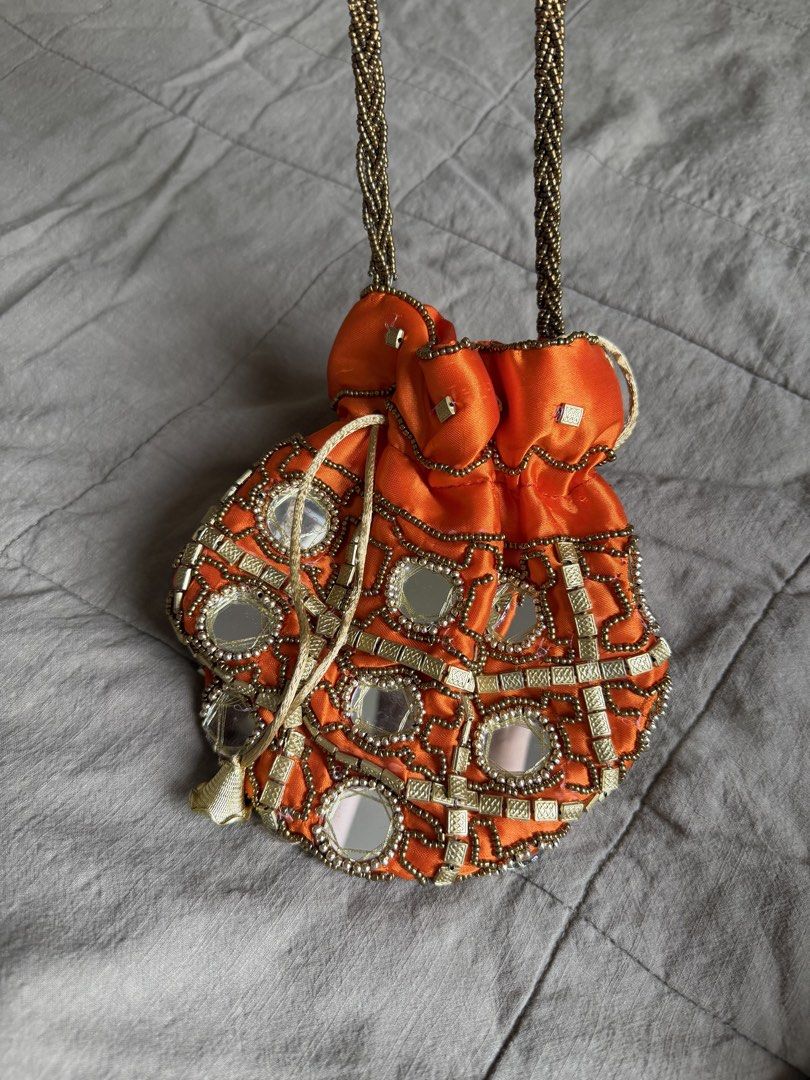 Orange Beaded Mirror Potli Bag with Gold Handle (Category: Purses & Pouches) located in Davao. Submitted by lyscapuno (Listing ID 1462685653, Image 1). Description: - Vibrant orange potli bag - Intricate beadwork and mirror embellishments - Braided gold handle - Secure drawstring closure - Ideal for parties and special occasions - Approximate dimensions: 7 inches (height) x 8 inches (width) - Unique and eye-catching design - bought in india by a 