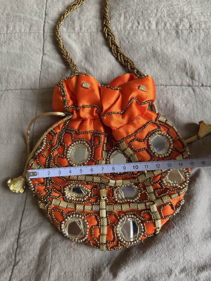 Orange Beaded Mirror Potli Bag with Gold Handle (Category: Purses & Pouches) located in Davao. Submitted by lyscapuno (Listing ID 1462685653, Image 3). Description: - Vibrant orange potli bag - Intricate beadwork and mirror embellishments - Braided gold handle - Secure drawstring closure - Ideal for parties and special occasions - Approximate dimensions: 7 inches (height) x 8 inches (width) - Unique and eye-catching design - bought in india by a 