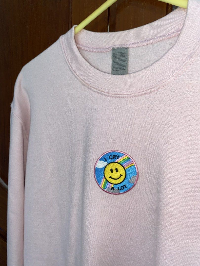 Pastel Pink Sweatshirt with "I Cry A Lot" Patch (Category: Coats, Jackets and Outerwear) located in Muntinlupa City. Submitted by oreonco (Listing ID 1462691148, Image 1). Description: From Chüssie Montreal - Light pink Gildan crewneck sweatshirt - Features a cute embroidered patch on the chest - Patch design: smiley face, rainbow, and clouds - Text on patch: "I Cry A Lot" - Super soft and comfortable material - Ideal for casual everyday wear.