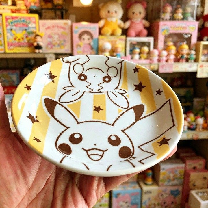 Pokemon Mister Donut Pikachu & Plusle/Minun Plate (Category: Character Goods) located in Iligan City. Submitted by sariranaw (Listing ID 1462881715, Image 2). Description: - Adorable Pokemon plate featuring Pikachu and either Plusle or Minun. - Unique Mister Donut collaboration design. - Features a fun yellow and white striped background with brown stars. - Ideal for serving snacks or as a small trinket dish. - Approximately 4-5 inches in diamete