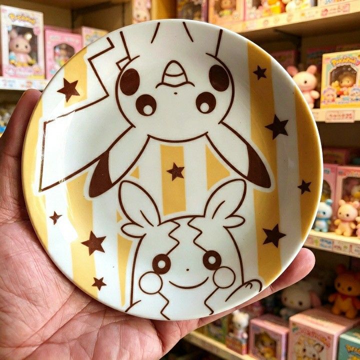 Pokemon Mister Donut Pikachu & Plusle/Minun Plate (Category: Character Goods) located in Iligan City. Submitted by sariranaw (Listing ID 1462881715, Image 3). Description: - Adorable Pokemon plate featuring Pikachu and either Plusle or Minun. - Unique Mister Donut collaboration design. - Features a fun yellow and white striped background with brown stars. - Ideal for serving snacks or as a small trinket dish. - Approximately 4-5 inches in diamete