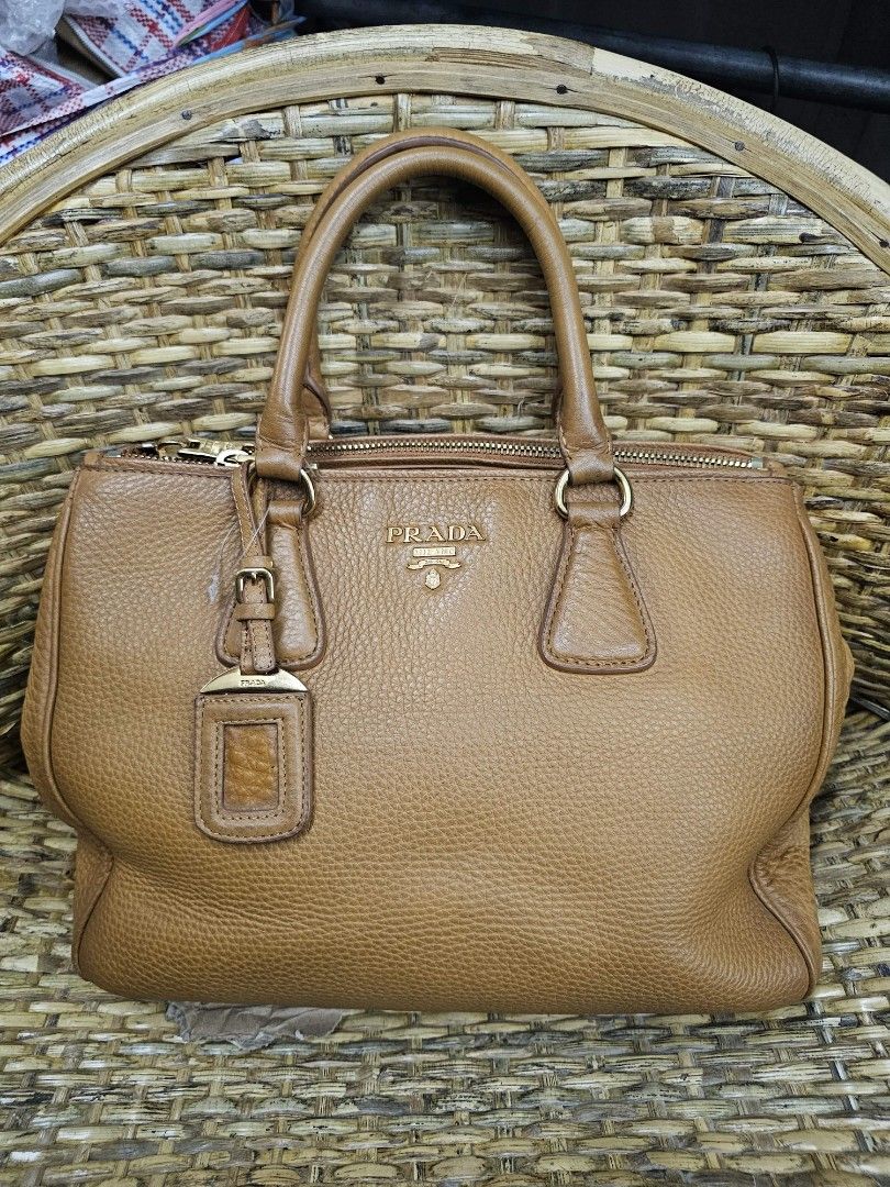 Prada Vitello (Category: Luxury Bags & Wallets) located in Bontoc. Submitted by athena_zia (Listing ID 1462846829, Image 1). Description: 🤎 PRADA Vitello Daino Top Handle Bag🤎 A timeless Prada classic in beautiful caramel brown grained leather, featuring the iconic Prada Milano logo, gold-tone hardware, and signature hanging tag. 🌸Condition: Good pre-loved condition 🌸 Normal signs of wear from previous use 🌸Few light rubs on the edges 🌸 Ove
