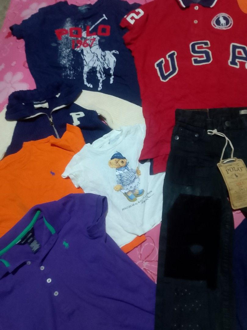 Ralph Lauren Bundle: Polos, T-shirts, Jeans (Category: Tshirts & Polo Shirts ) located in Iloilo. Submitted by janillthrifted (Listing ID 1462863547, Image 3). Description: - Bundle of Ralph Lauren items - Includes: Navy blue t-shirt with horse graphic - Red 'USA' polo shirt - White 'Polo Bear' t-shirt - Orange polo shirt - Purple long-sleeve polo shirt - Navy and cream jacket - Black jeans - Perfect mix of tops and bottoms for your wardrobe!.