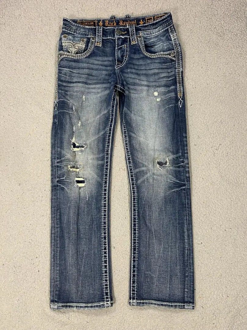 Rock Revival Jeans Distressed Blue Denim (Category: Jeans) located in Caloocan City. Submitted by thriftnigab2 (Listing ID 1462869122, Image 2). Description: - Rock Revival jeans - Distressed blue wash - White contrast stitching - Signature Rock Revival logo on back pockets - Rips and wear on front - Designed in USA, Made in Vietnam - Perfect for casual wear.