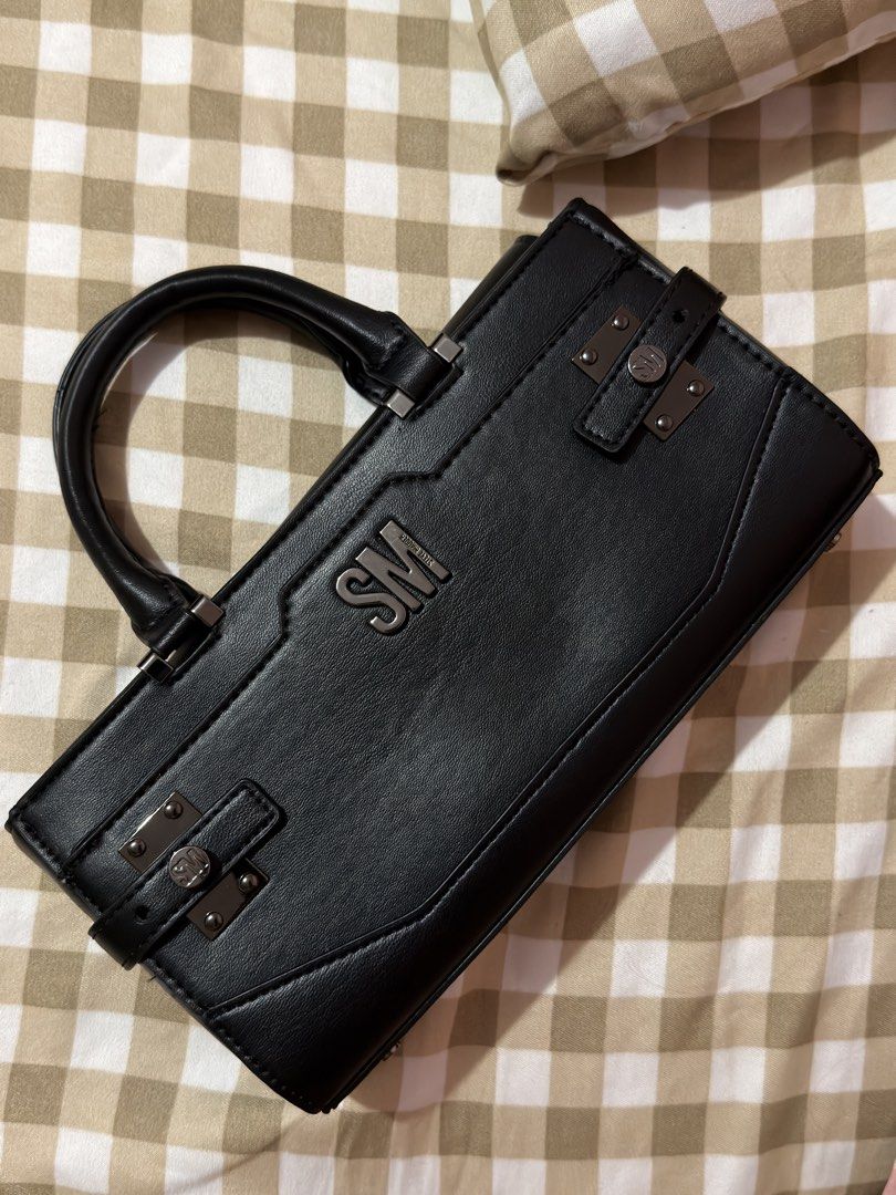 Steve Madden Black Handbag (Category: Luxury Bags & Wallets) located in Taguig. Submitted by aeriyaaaa (Listing ID 1462693919, Image 3). Description: - Classic black Steve Madden handbag - Versatile top handle and detachable shoulder strap - Interior zippered compartment for secure storage - Elegant metal hardware details on the front - Clean and timeless design, ideal for everyday or evening wear.