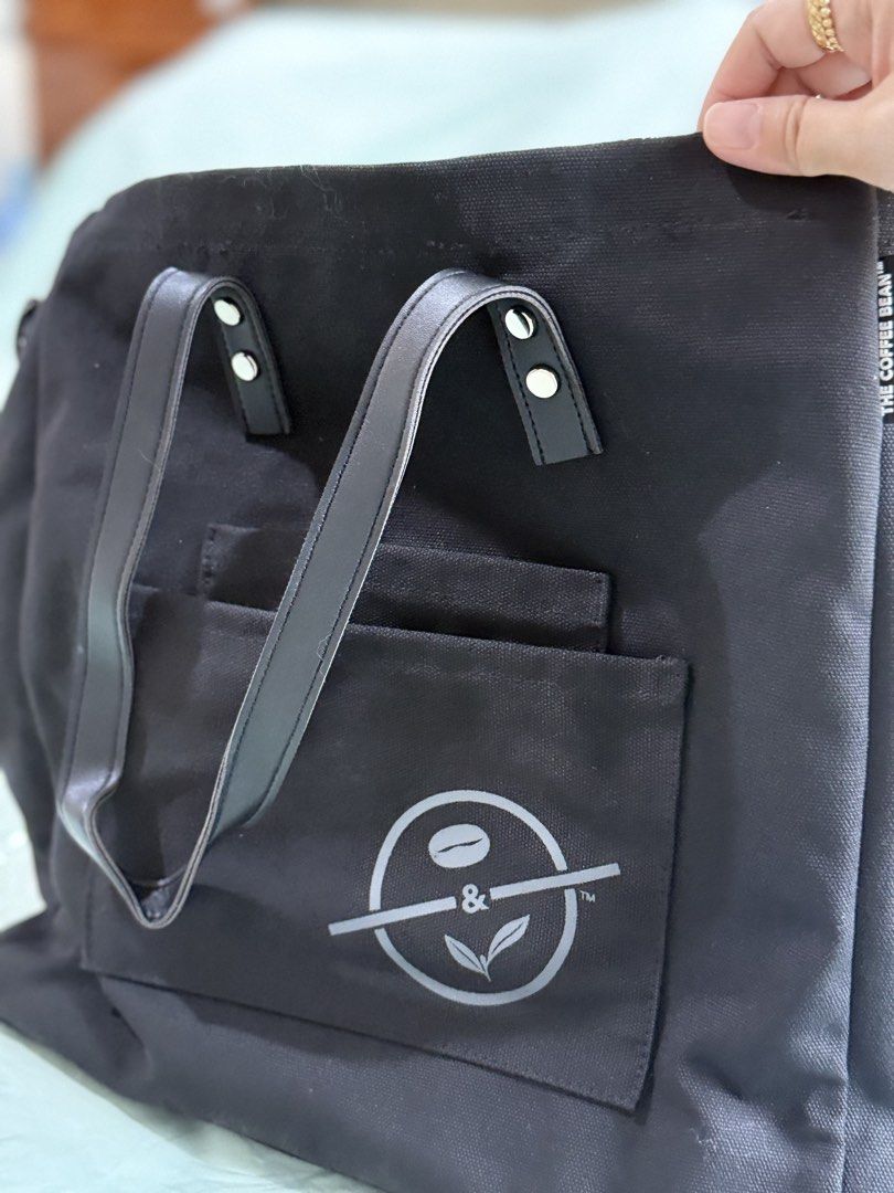 The Coffee Bean & Tea Leaf Voyager Tote Bag (Category: Tote Bags) located in Manila. Submitted by purplebunnie1 (Listing ID 1462769007, Image 2). Description: - Brand: The Coffee Bean & Tea Leaf - Material: Black Canvas - Features: Leather handles, front pocket with brand logo - Condition: Brand new with original tag - Ideal for: Everyday use, travel, shopping.