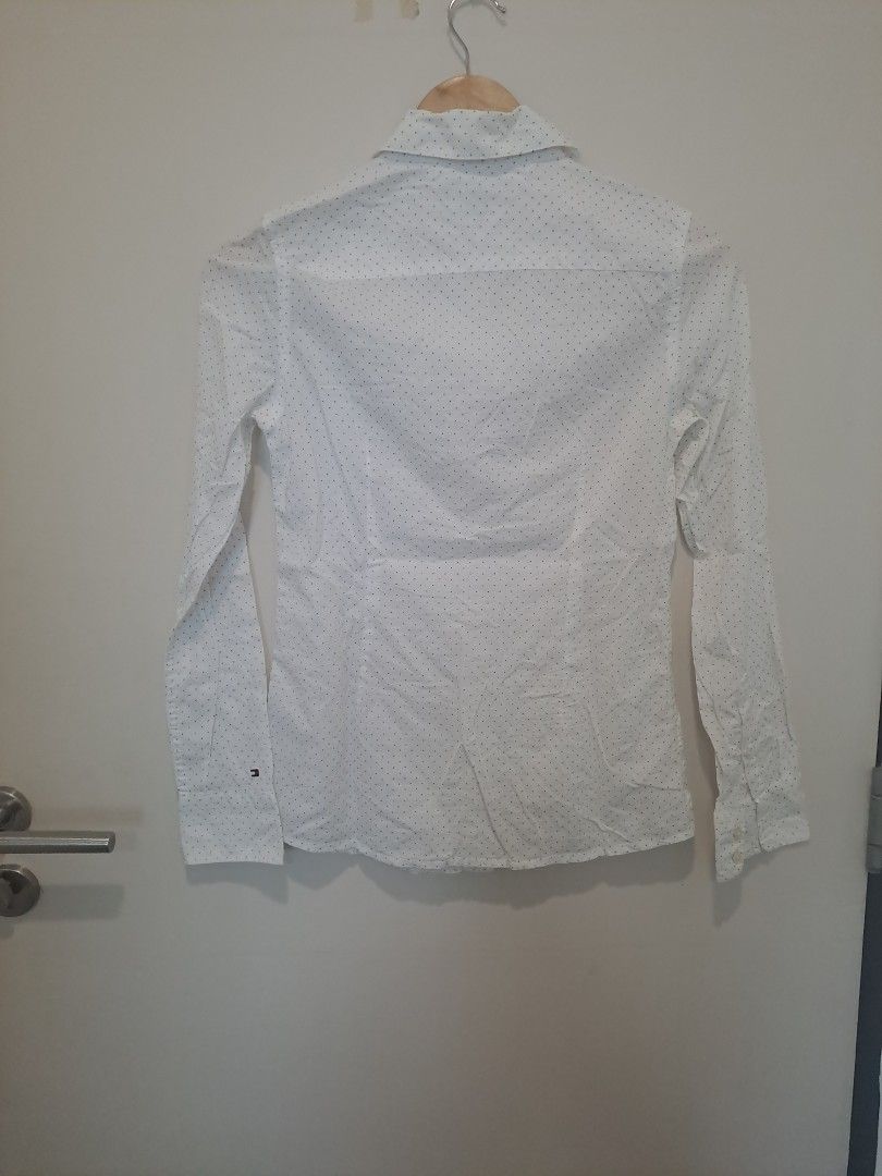 Tommy Hillfiger longsleve (Category: Longsleeves) located in Manila. Submitted by joanbalde39643 (Listing ID 1462778213, Image 3). Description: The image shows a Tommy Hilfiger women's white long-sleeve button-down shirt featuring a subtle all-over dark polka dot or micro-print pattern. It features a classic pointed collar, a central button placket, long sleeves with buttoned cuffs, and the signature tiny Tommy Hilfiger flag logo embroidered on t