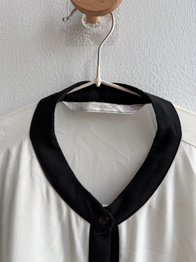 TRAFALUC White Black Long Sleeve Blouse (Category: Blouses) located in Makati City. Submitted by ariannelaz54133 (Listing ID 1462836022, Image 2). Description: - White blouse with elegant black sheer sleeves. - Features black trim around the collar and down the front. - Convenient button closure at the neck. - Simple and classic design, perfect for dressing up or down..